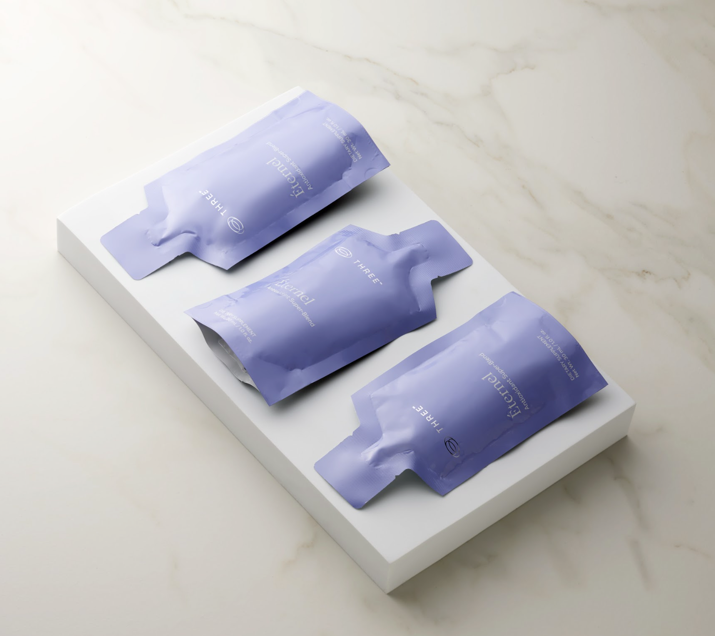 Three Éternel Antioxidant Super-Blend supplement pouches displayed together, featuring THREE’s formula designed to support cellular-level antioxidant wellness.