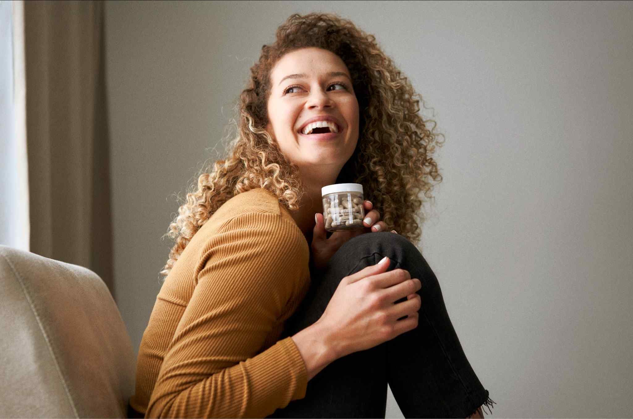 Woman holding a bottle of Imúne Total Body Immune Support, a daily supplement formulated with vitamins, minerals, and complementary ingredients for immune wellness.