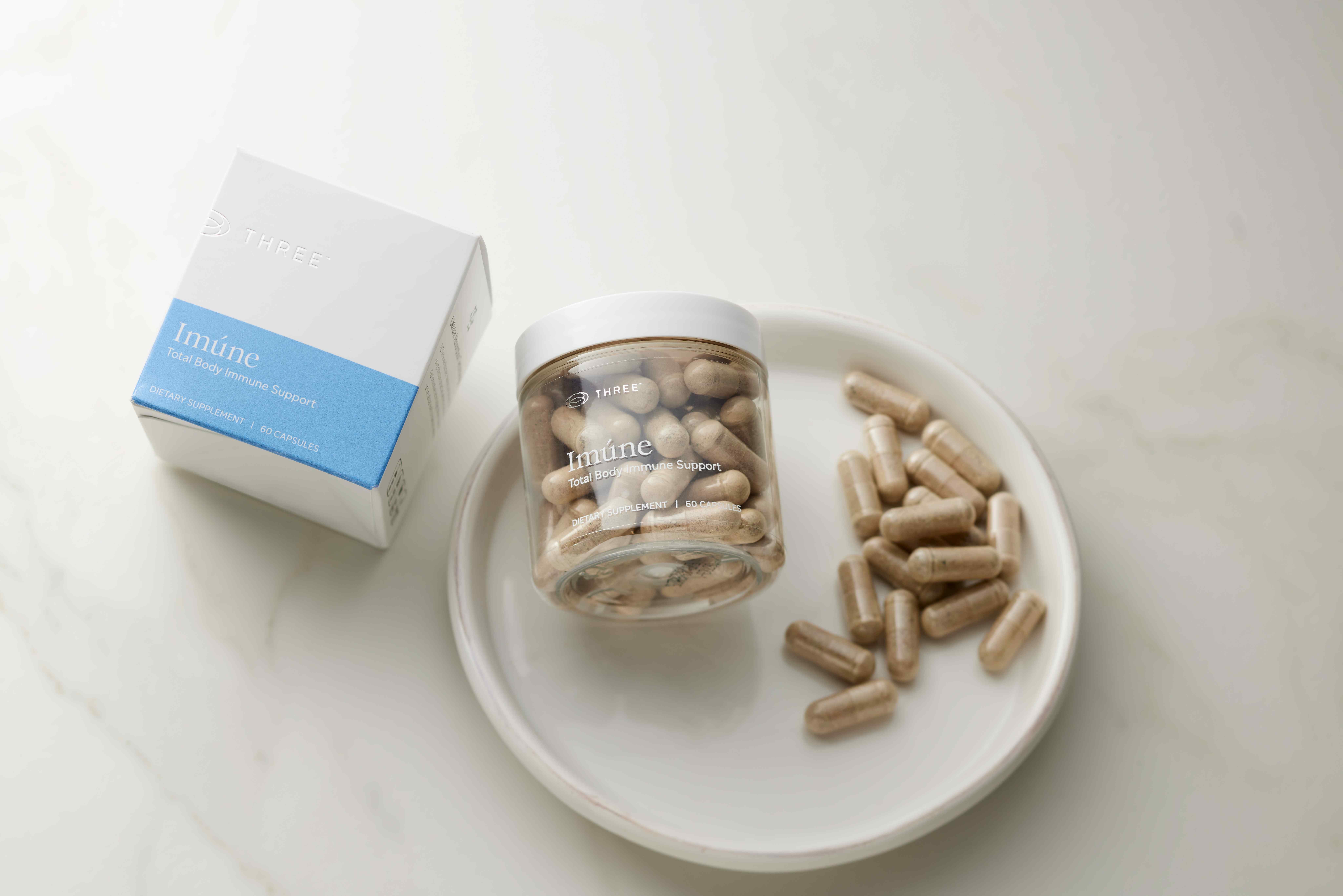 Imúne capsules displayed alongside the product packaging, emphasizing a simple daily immune support formula designed to work at the cellular level and support whole-body resilience.