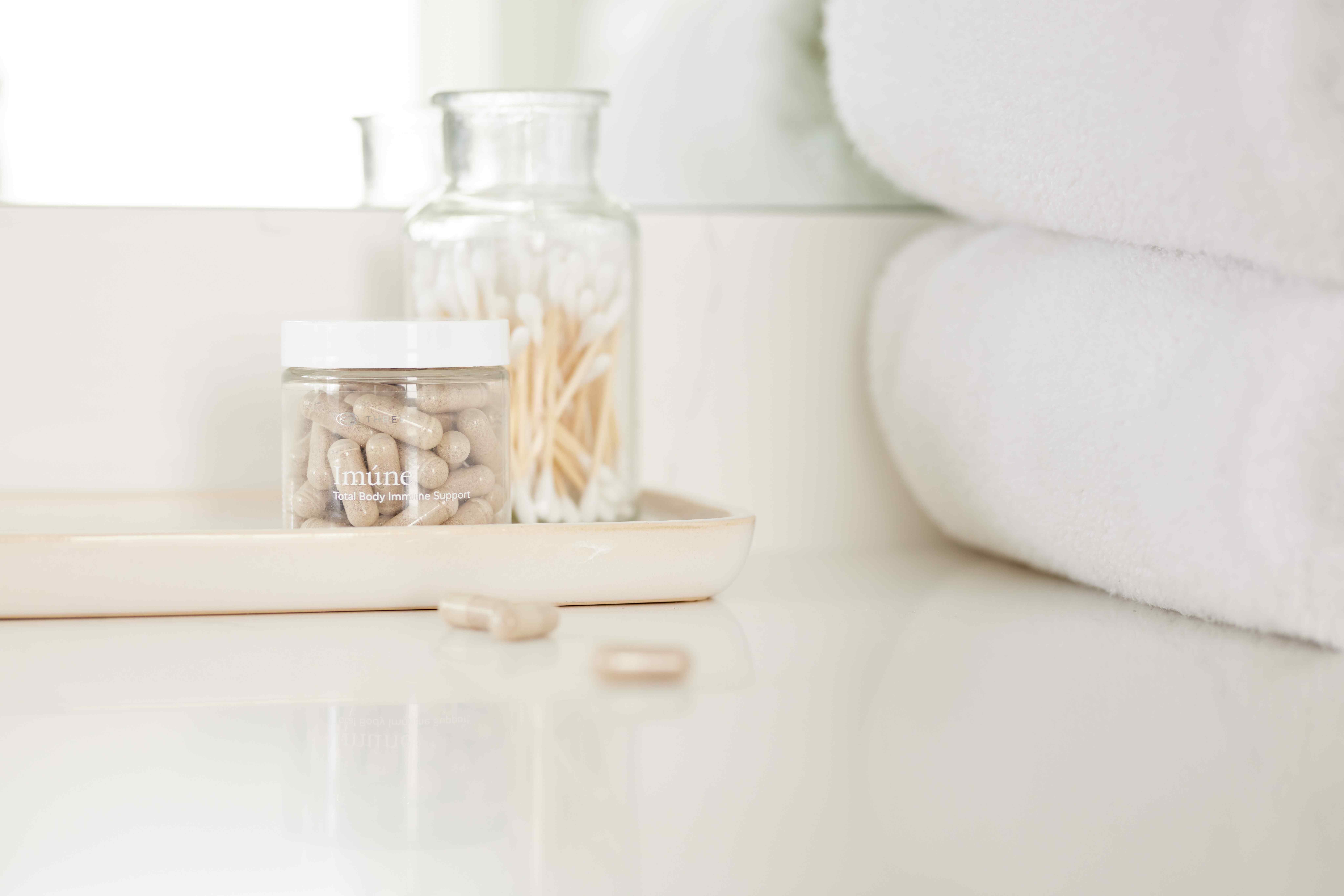 A minimal, clean setting featuring a bottle of Imúne capsules, reflecting THREE’s focus on cellular absorption technology and thoughtfully formulated immune system support.