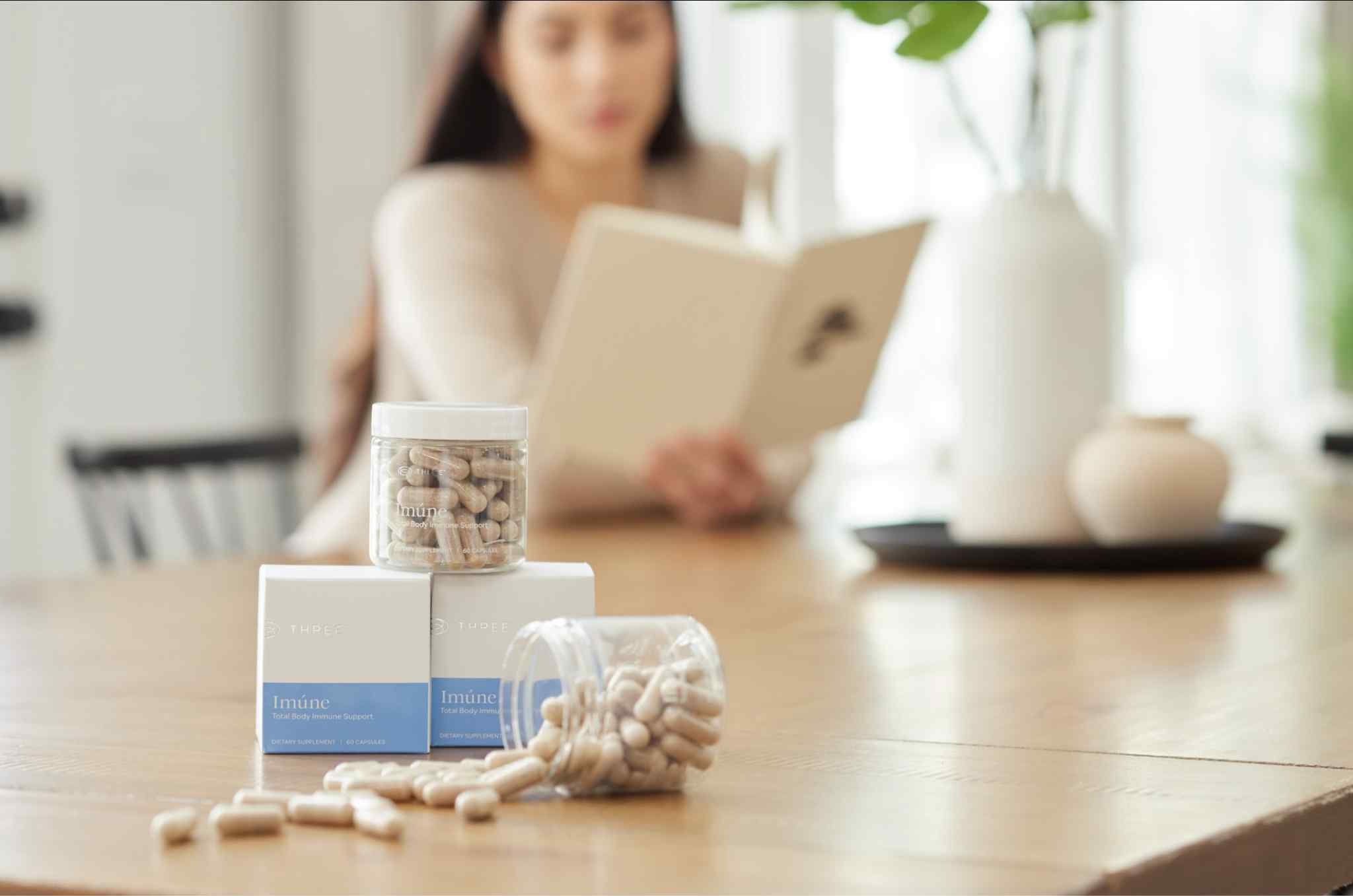 Imúne Total Body Immune Support supplement bottles, capsules, and packaging displayed on a table as part of a daily immune wellness routine.