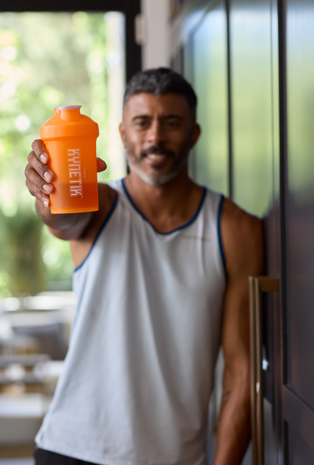 Person holding a Kynetik shaker bottle to promote clean caffeine, hydration, and sustained energy for active summer days.