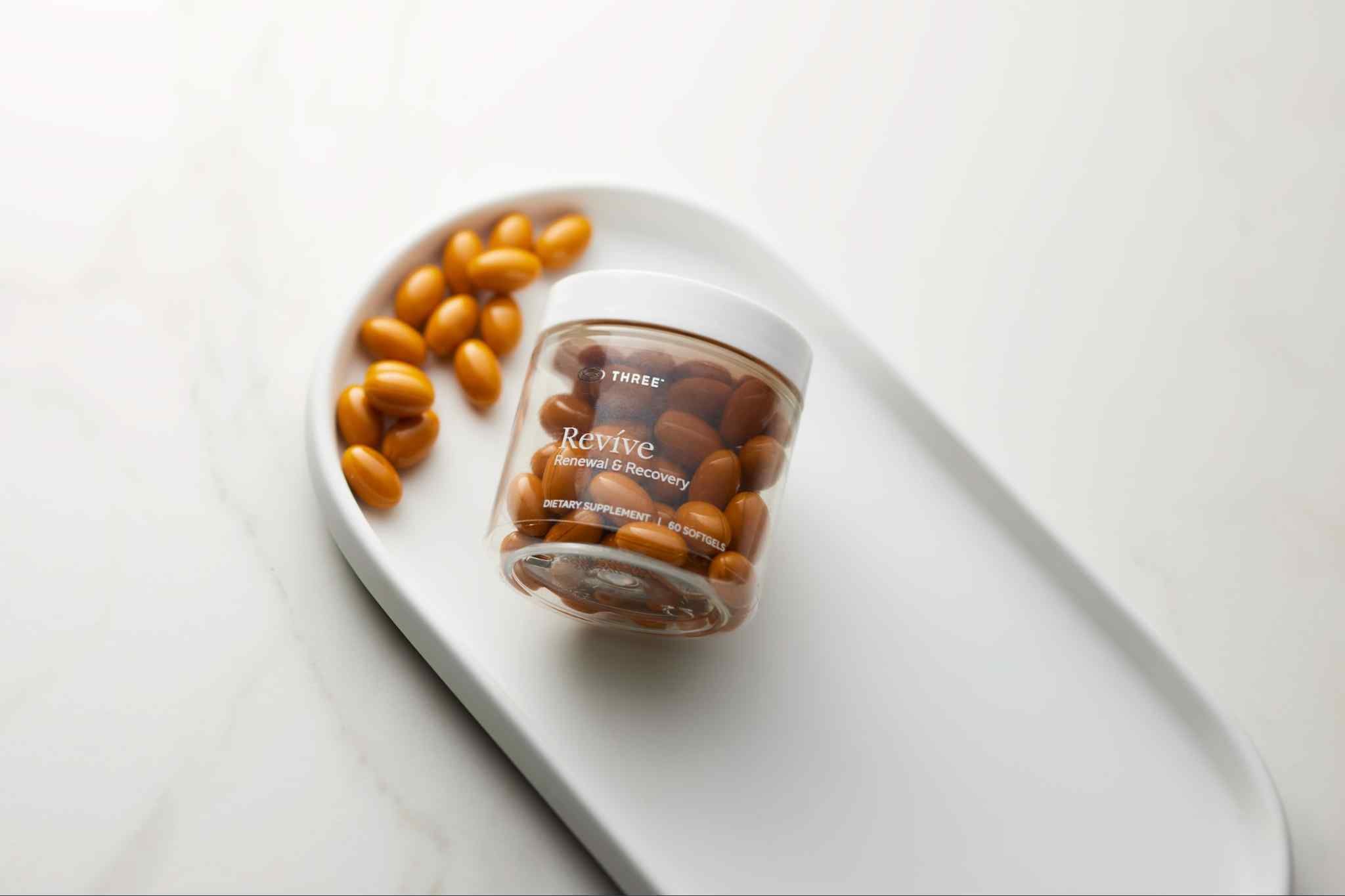 Bottle of THREE Revíve Renewal & Recovery with softgels displayed on a white tray. Revíve combines Boswellia with complementary compounds in a formula designed to support joint health, mobility, and recovery.