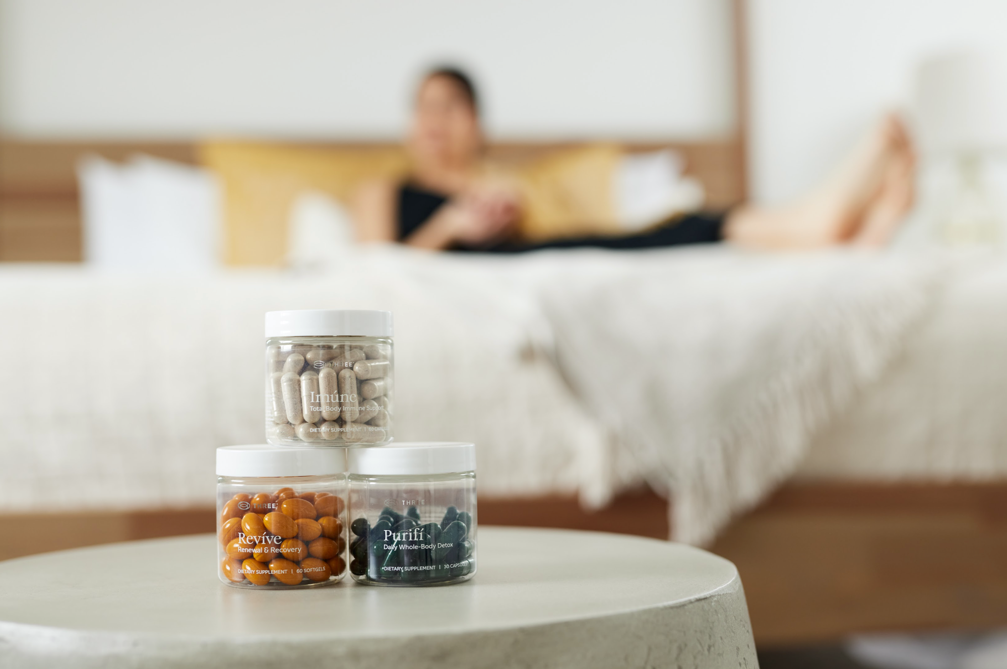 THREE International Imúne, Revíve, and Purifí supplements displayed together in a relaxed home setting. The image reflects THREE’s focus on science-driven wellness products designed to support everyday health and well-being.