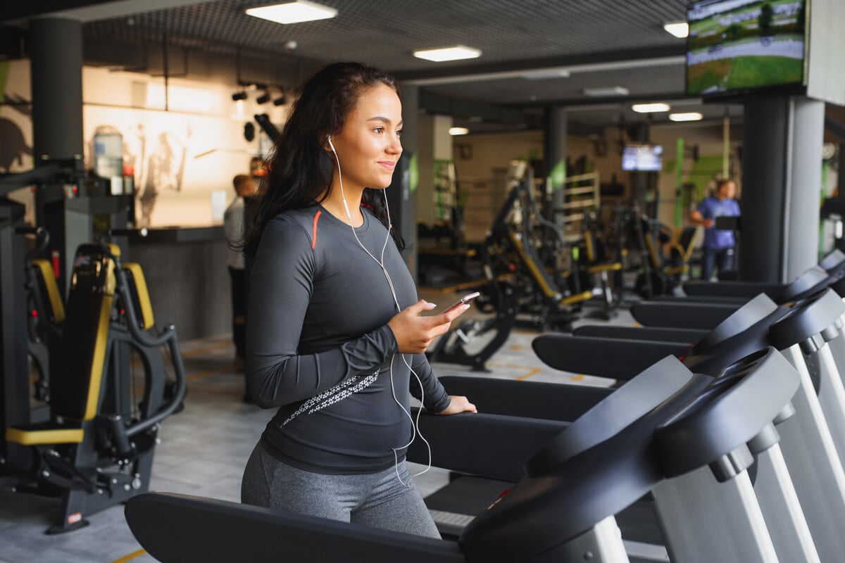 a woman smiling while on a treadmill achieving her fitness goals in 2025